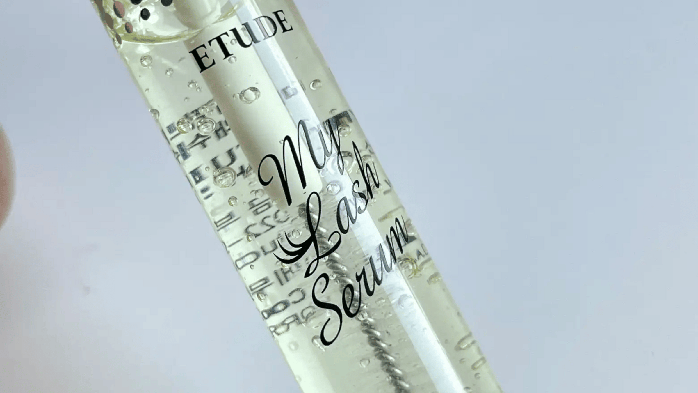 Bilden visar Etudes "My Lash Serum" i en genomskinlig flaska. Den klara vätskan med bubblor ger ett estetiskt intryck. Produkten är avsedd för ögonfransarnas hälsa och tillväxt.