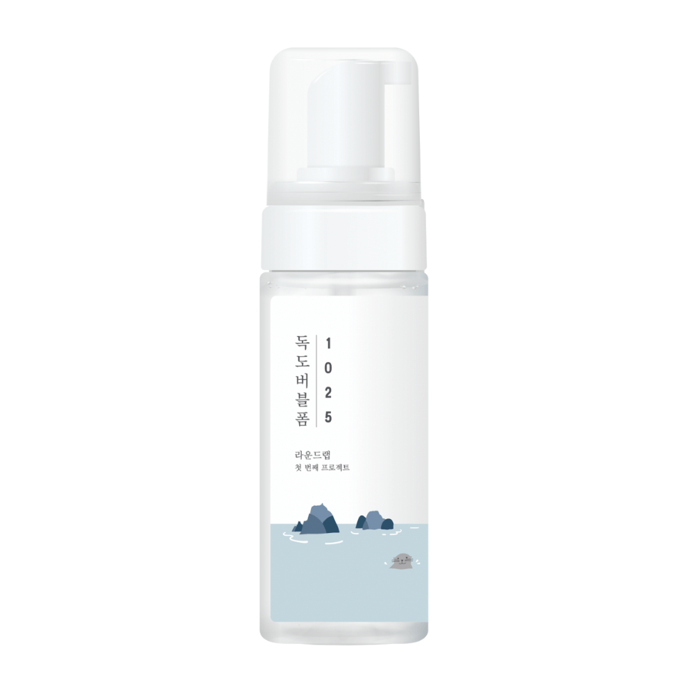 1025 Dokdo Bubble Foam" ist ein Gesichtsreinigungsprodukt von ROUND LAB, verpackt in einer weißen Pumpflasche mit einfachem und sauberem Design, verziert mit Text und minimalistischen Illustrationen von Meereslandschaften. 