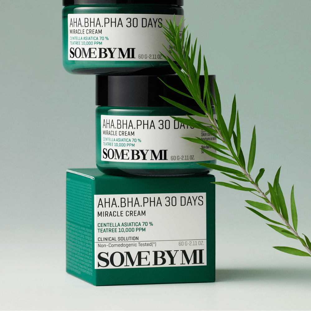 Ein Bild, das zwei Dosen von "SOME BY MI AHA, BHA, PHA 30 Days Miracle Cream" zeigt, die auf einer grün getönten Fläche gestapelt sind. Die Creme, die reich an Centella Asiatica und tea tree-Öl ist, ist darauf ausgelegt, die Hautqualität zu verbessern und Problemhaut zu lindern. Wirkt feuchtigkeitsspendend und beruhigend.