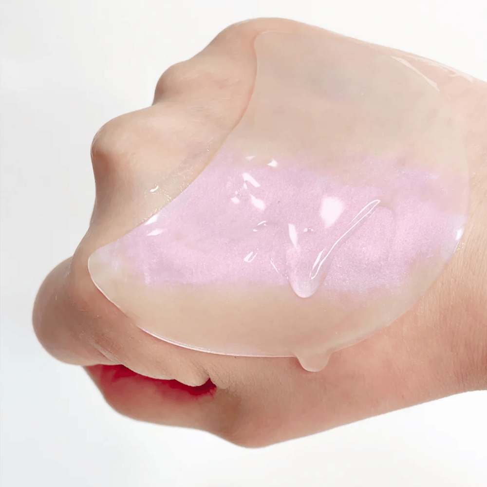 Rosa Hydrogel-Augenpflaster mit Retinol wird auf einer Hand gezeigt, feuchtigkeitsspendende und strahlende Formel.