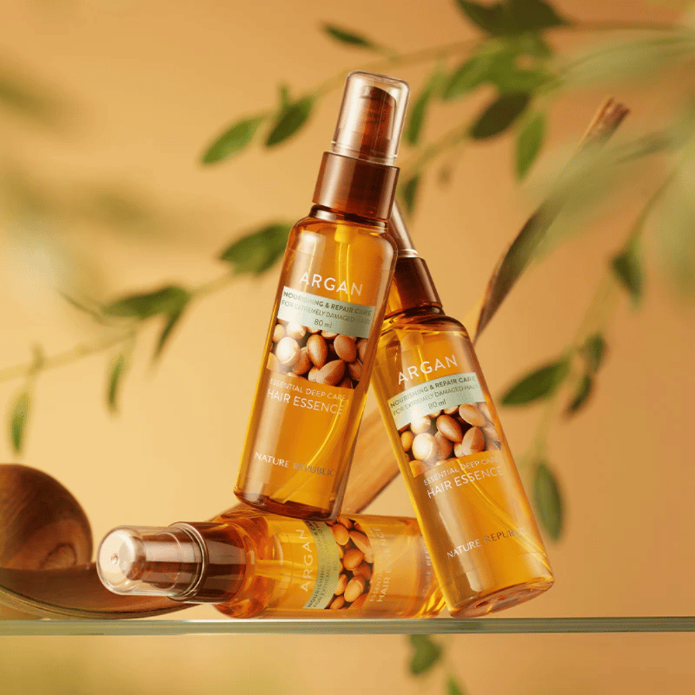 Drei Flaschen von Nature Republic Argan Essential Moisture Hair Oil mit Arganöl – nährt, verleiht Glanz und repariert geschädigtes Haar.