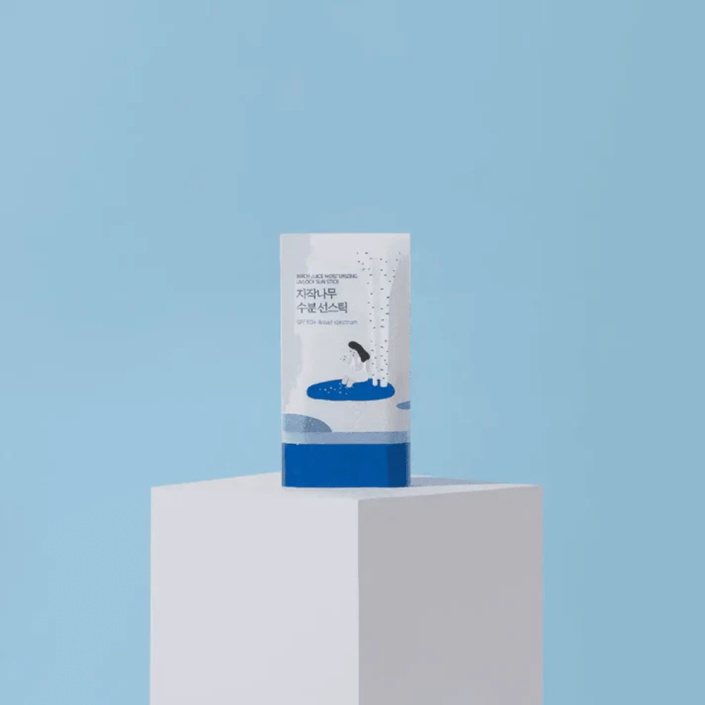 ROUND LAB Birch Juice Moisturizing Sun Stick SPF50+ steht auf einem Podest vor blauem Hintergrund – feuchtigkeitsspendender Sonnenschutz im Stickformat