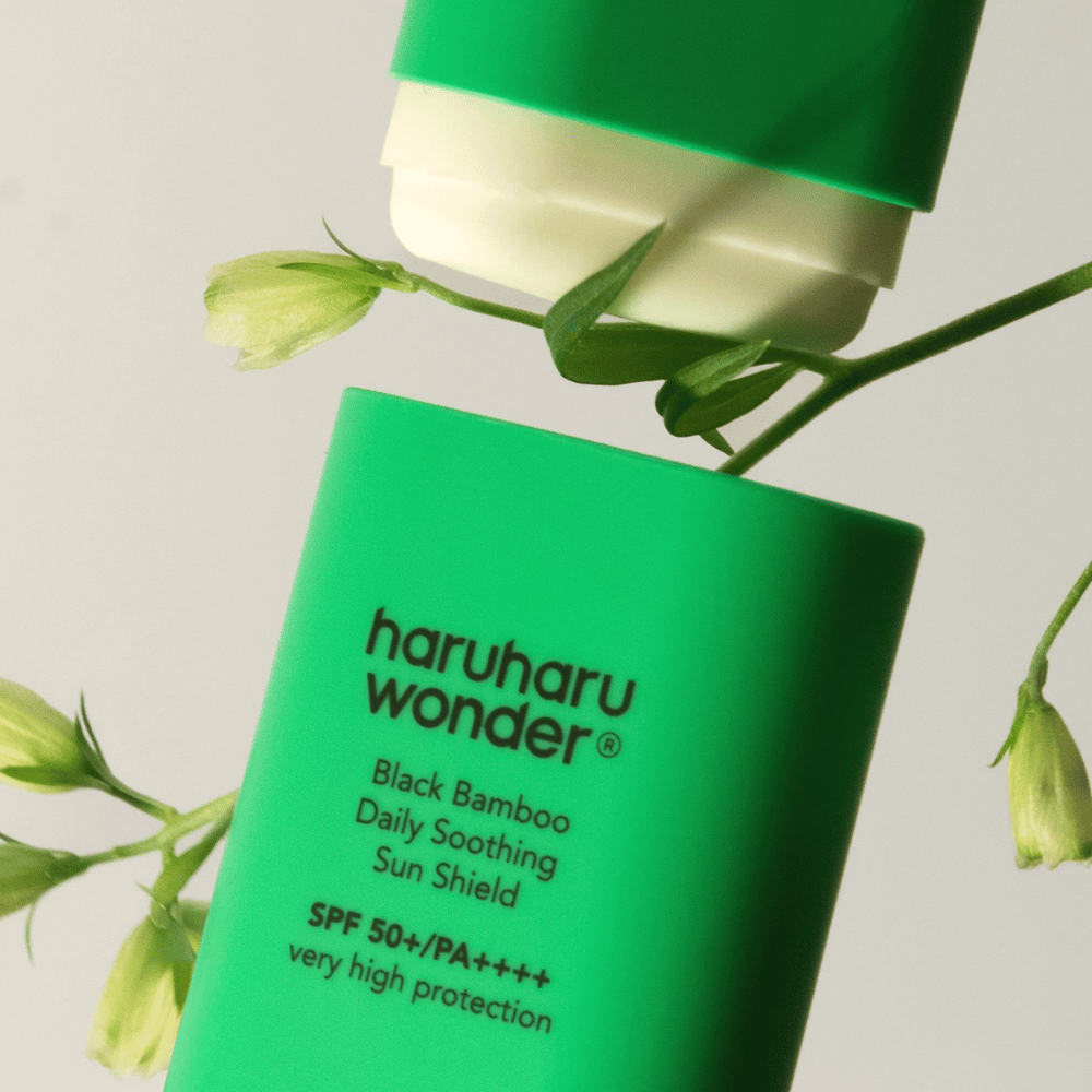 Nahaufnahme von Haruharu Wonder Black Bamboo Daily Soothing Sun Shield – ein grüner Sonnenschutz in Stiftform mit SPF 50+ PA++++, umgeben von grünen Pflanzendetails.