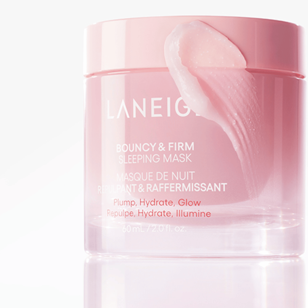 Nahaufnahme von Laneige Bouncy & Firm Sleeping Mask in einem rosa Glasgefäß, mit einem Teil der Maske, der auf den Rand des Deckels aufgetragen ist. Das Produkt ist dafür gedacht, Volumen, Feuchtigkeit und Glanz zu verleihen. Das Glasgefäß fasst 60 ml und hat den Text "Plump, Hydrate, Glow."
