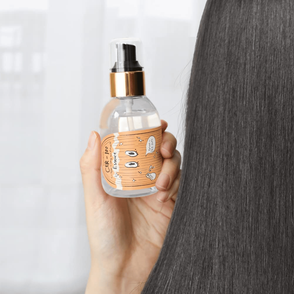 Eine Person hält CER-100 Hair Essence neben langem, glänzendem Haar, um Weichheit und Pflege zu zeigen.