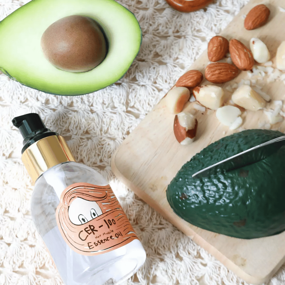 Elizavecca CER-100 Hair Muscle Essence Oil Zutaten – Nahaufnahme mit Avocado und Pflanzenölen, die ein nährstoffreiches Haaröl zeigen, das hilft, das Haar zu erweichen und zu pflegen.