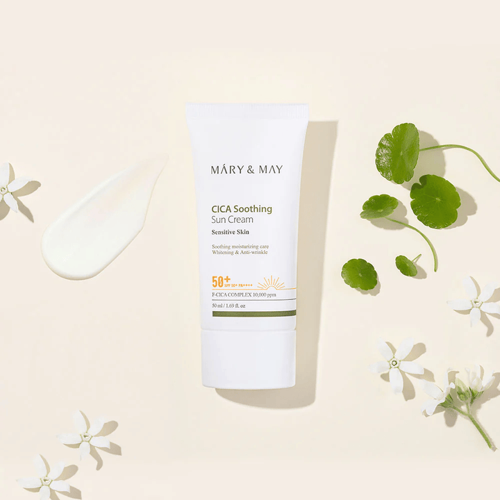 Mary&May CICA Soothing Sun Cream SPF50+ PA++++ präsentiert zusammen mit einer Creme-Textur, Centella-Blättern und weißen Blumen. Das Bild hebt die beruhigenden Eigenschaften des Produkts und den Fokus auf empfindliche Haut hervor.