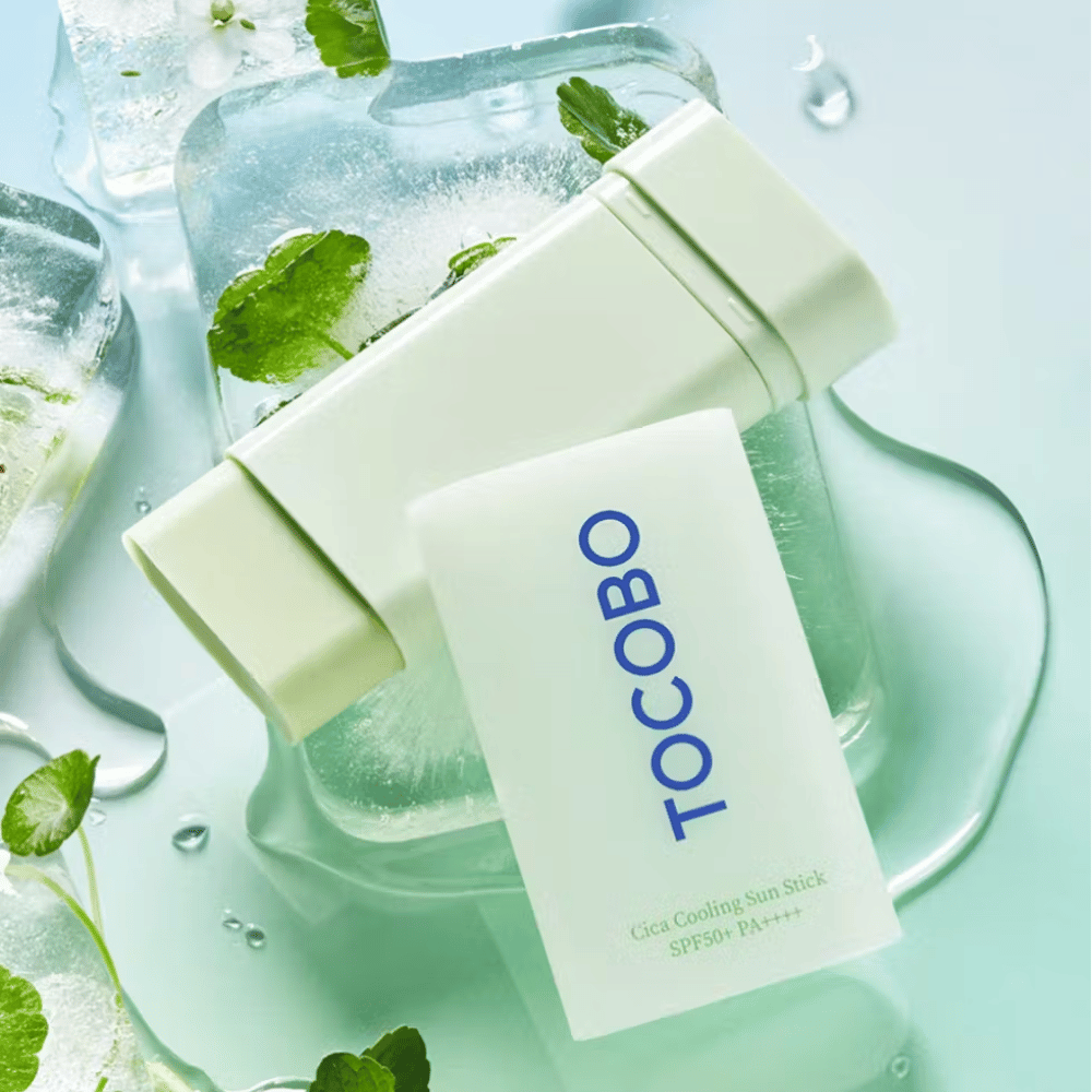 Tocobo Cica Cooling Sun Stick SPF50+ PA++++ auf Eiswürfeln mit grünen Pflanzenblättern, vermittelt ein kühlendes und erfrischendes Gefühl.