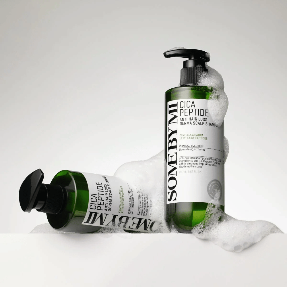 Zwei Flaschen von SOME BY MI Cica Peptide Anti Hair Loss Derma Scalp Shampoo bedeckt mit Schaum, stehend und liegend auf weißem Hintergrund.