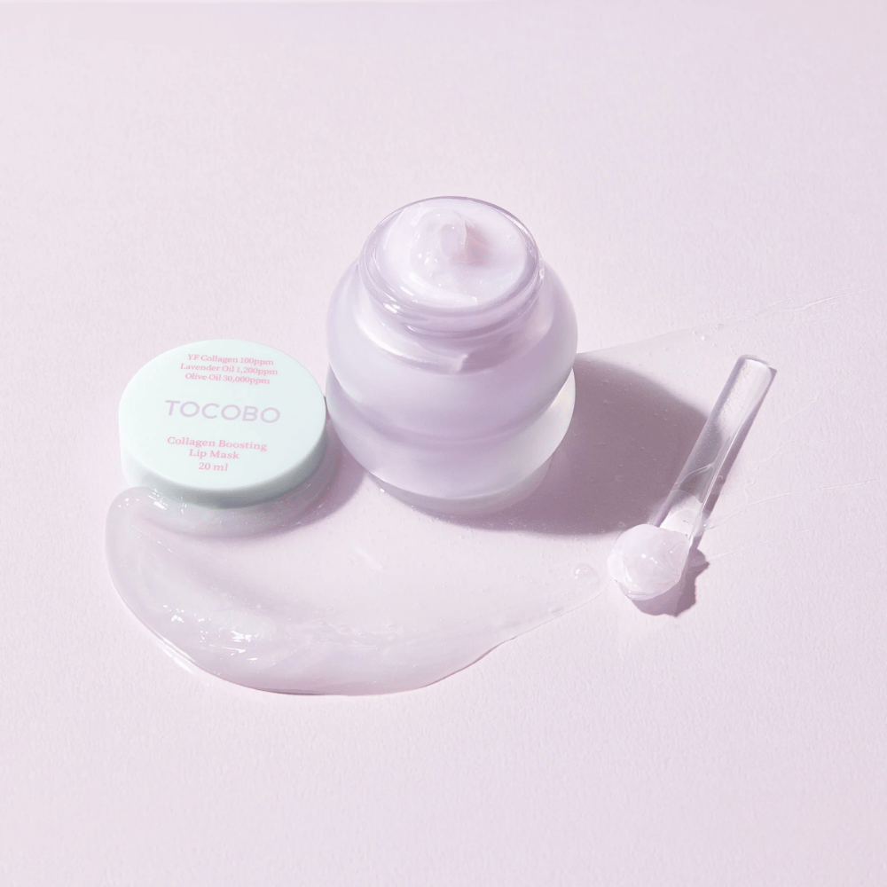 Offenes Glas TOCOBO Collagen Boosting Lip Mask mit Spatel und verstreuter lila Creme auf helllila Hintergrund.