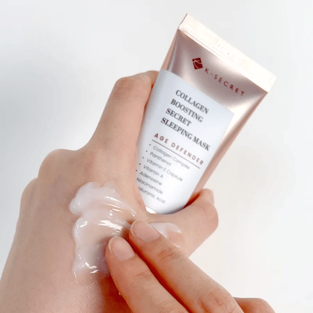 Eine Hand hält Collagen Boosting Secret Sleeping Mask, während die andere eine großzügige Menge Creme auf den Handrücken aufträgt – zeigt die Konsistenz und Anwendung des Produkts.