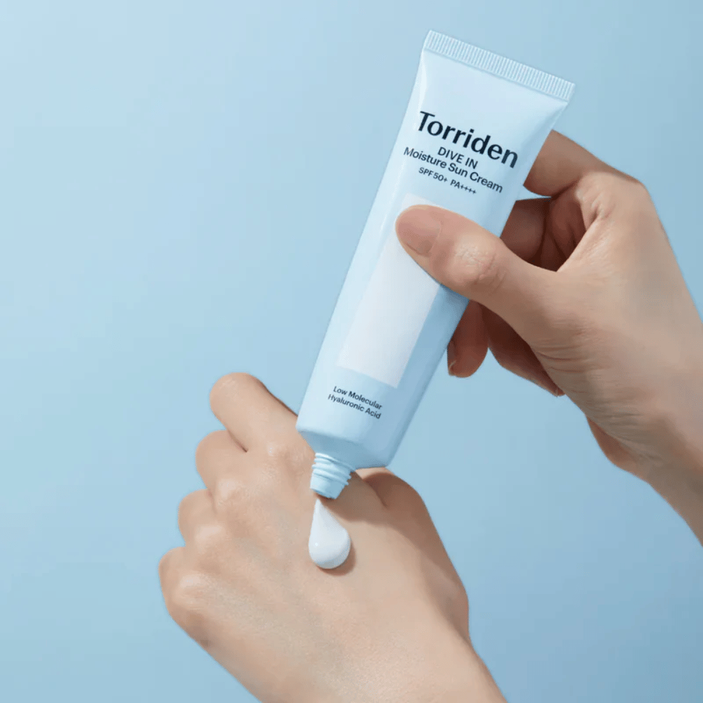 Torriden DIVE-IN Moisture Sun Cream SPF50+ PA++++ wird auf die Hand aufgetragen, um die leichte und cremige Konsistenz der feuchtigkeitsspendenden Sonnencreme zu zeigen.