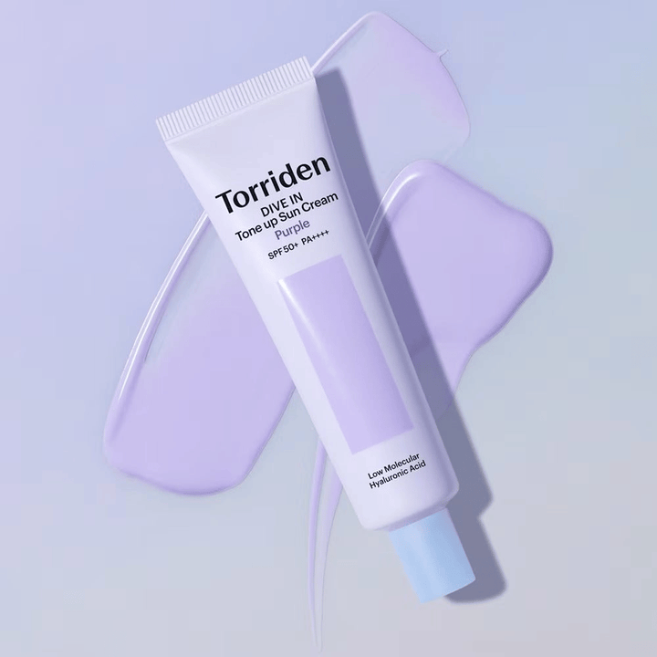 Torriden DIVE IN Tone Up Sun Cream Purple auf verschmierter lila Creme platziert, die den hauttonausgleichenden und strahlenden Effekt hervorhebt.