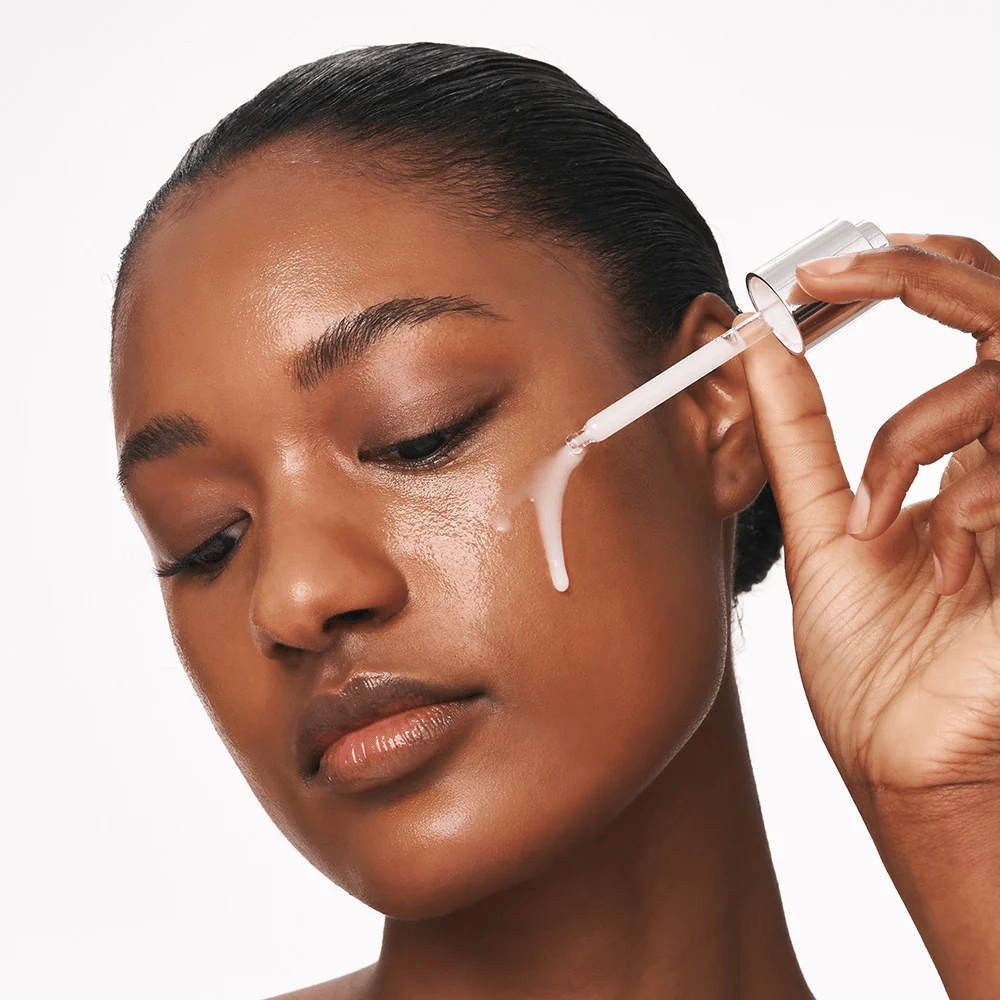 Person trägt Deep Collagen Power Boosting Cream in Serum mit Pipette auf die Wange auf. Das Serum sorgt für straffere, hydratisierte Haut mit Ausstrahlung.