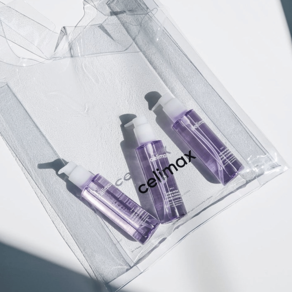 Drei Flaschen von Celimax Derma Nature Fresh Blackhead Jojoba Cleansing Oil in lila Verpackung, platziert in einer transparenten Tasche mit dem Logo 'celimax'.
