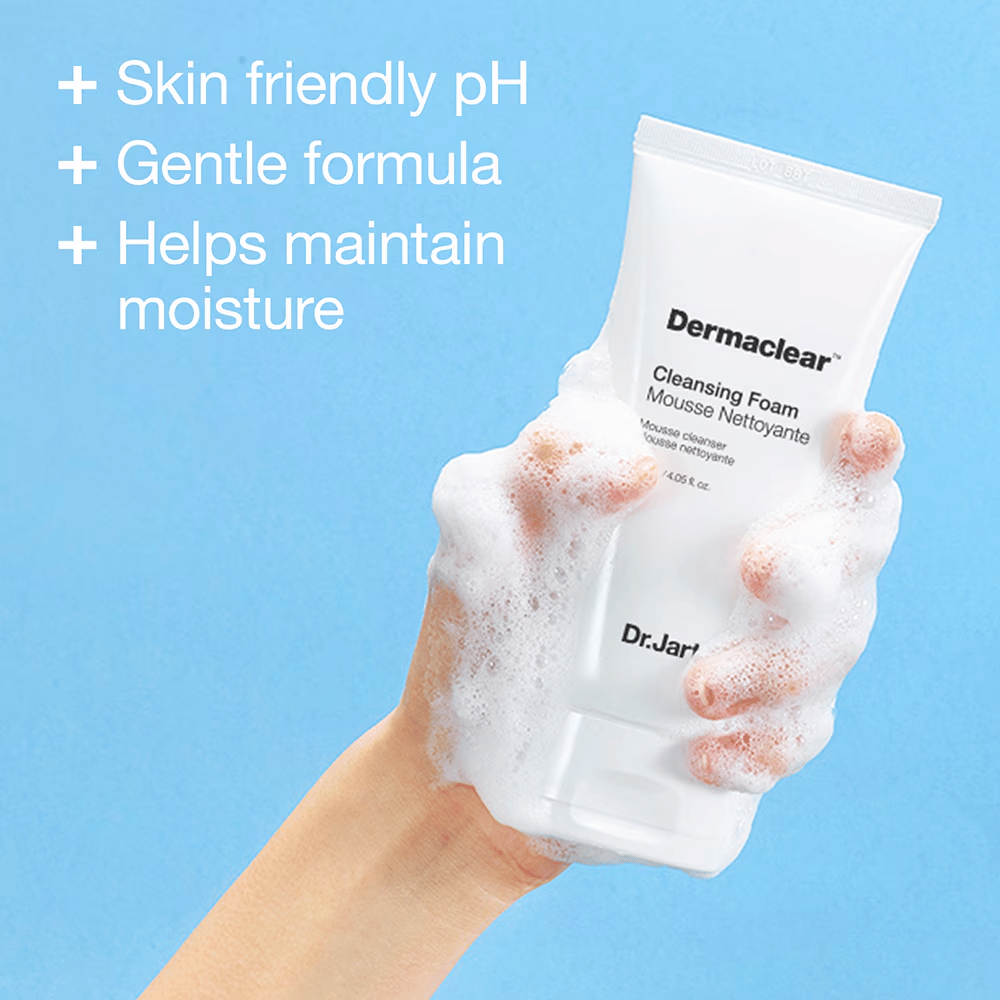 Hand, die mit Schaum bedeckt ist, hält Dr.Jart+ Dermaclear Cleansing Foam gegen blauen Hintergrund, mit Text, der hautfreundlichen pH-Wert, milde Formel und feuchtigkeitsspendende Eigenschaften hervorhebt.