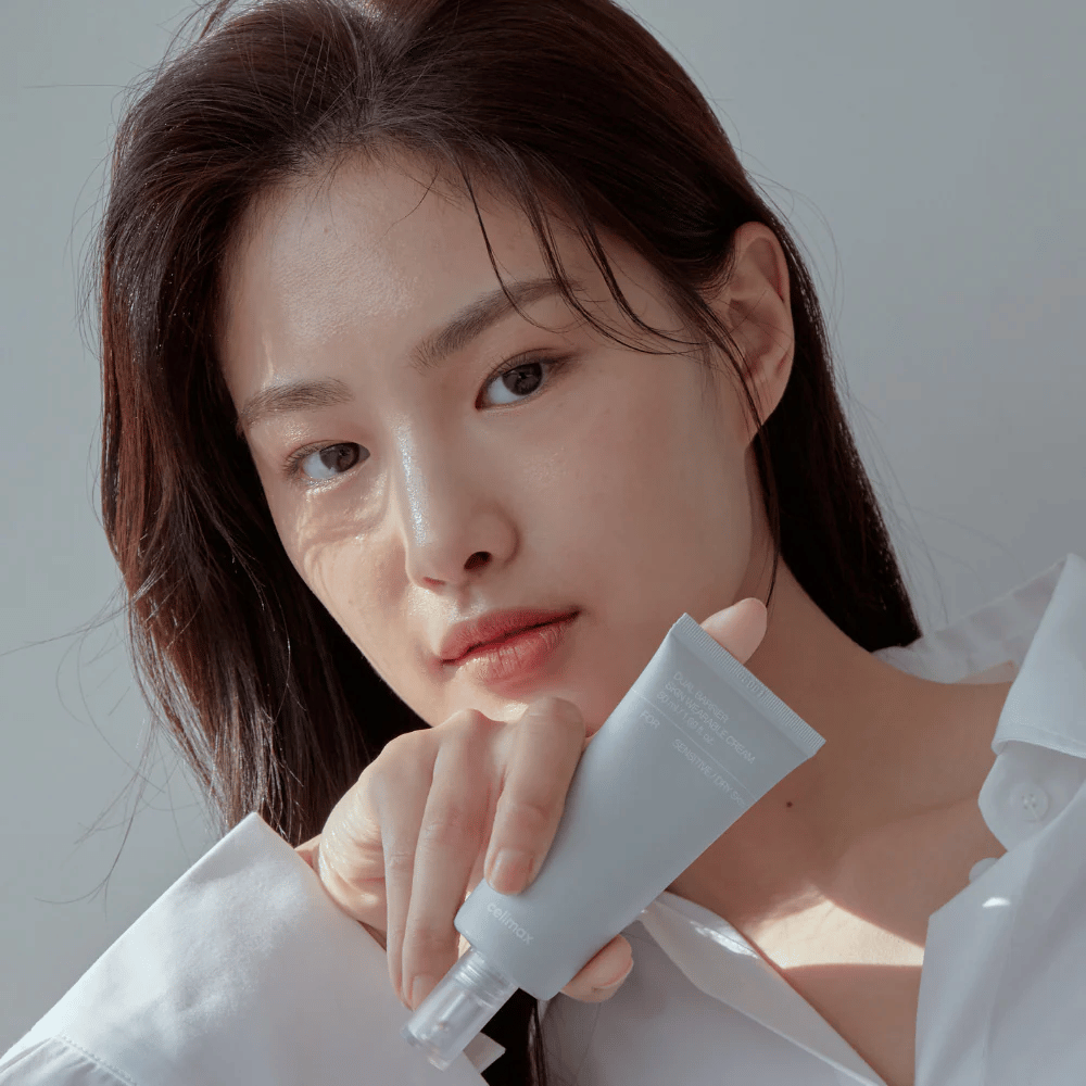 Modell, das Celimax Dual Barrier Skin Wearable Cream hält, beruhigende und barriereverstärkende Gesichtscreme für empfindliche und trockene Haut.