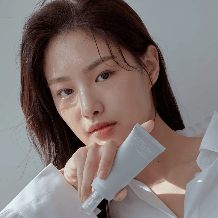 Modell, das Celimax Dual Barrier Skin Wearable Cream hält, beruhigende und barriereverstärkende Gesichtscreme für empfindliche und trockene Haut.