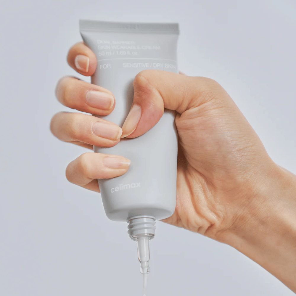 Hand, die Celimax Dual Barrier Skin Wearable Cream aufträgt, barriereverstärkende Gesichtscreme für empfindliche und trockene Haut, die langanhaltende Feuchtigkeit spendet und die Hautbarriere schützt.