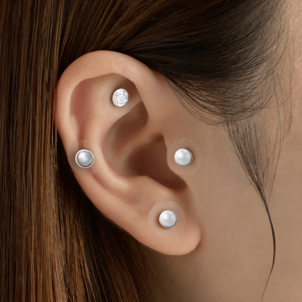 Nahaufnahme eines Ohrs mit mehreren RETURNITY Ear Therapy Acupressure Patch, die auf verschiedenen Bereichen des Ohrs für Akupressur und einen stilvollen Look angebracht sind.