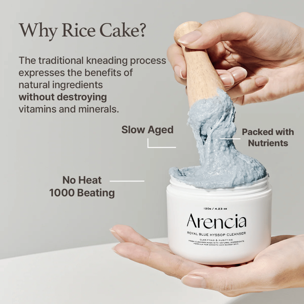 Hand, die das Reinigungsgefäß "Arencia Royal Blue Hyssop Cleanser" mit einem Holzlöffel hält, der die blaue, mochi-ähnliche Reinigungspaste aufnimmt. Der Text im Bild beschreibt die Vorteile des Reismehlprozesses, wie "Keine Hitze", "1000 Schläge", "Langsam gereift" und "Voller Nährstoffe".