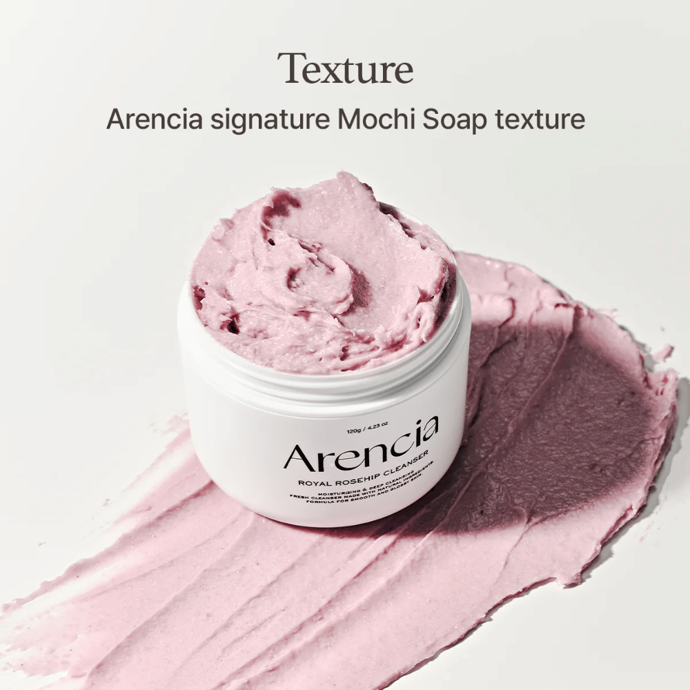 Behälter mit Arencia Royal Rosehip Cleanser ist auf einer verschmierten rosa Reinigung mit mochi-ähnlicher Textur zu sehen. Der Text darüber beschreibt das Produkt als Arencias Signaturtextur.