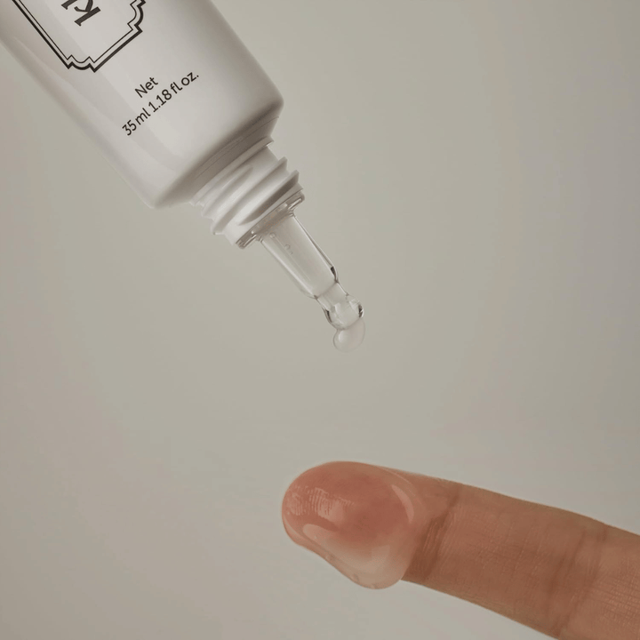 Detailbild, auf dem ein klares, leichtes Gel aus der schmalen Spitze auf einen Finger aufgetragen wird. Das Bild veranschaulicht die transparente, gelbasierte Konsistenz des Produkts und die präzise Anwendung rund um die Augenpartie.
