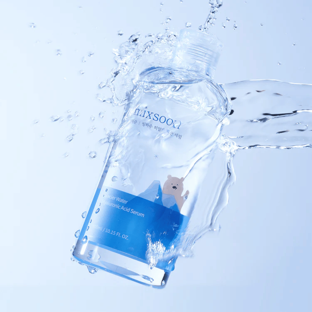 Mixsoon Glacier Water Hyaluronic Acid Serum-Flasche mit blauem Etikett und Eisbärenmotiv, umgeben von spritzendem Wasser vor hellblauem Hintergrund.