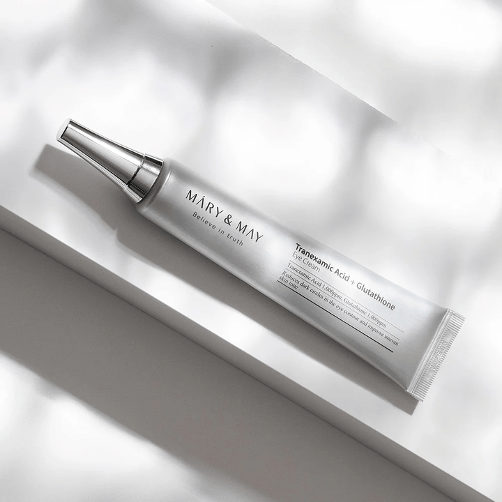 Nahaufnahme von Mary&May Tranexamic Acid + Glutathione Eye Cream mit Metallapplikator, entwickelt, um dunkle Ringe aufzuhellen und den Hautton um die Augen auszugleichen.