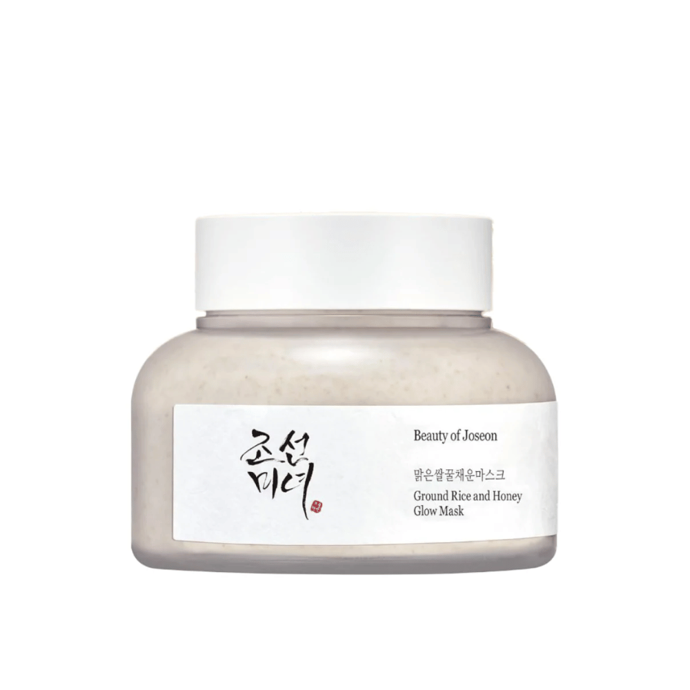 Ein Glas "Beauty of Joseon Ground Rice and Honey Glow Mask". Die Verpackung ist einfach mit einem weißen Deckel und einem Etikett, das den Produktnamen und die Inhaltsstoffe sowohl auf Koreanisch als auch auf Englisch präsentiert. Das Produkt ist darauf ausgelegt, der Haut Glanz und Nährstoffe zu verleihen.