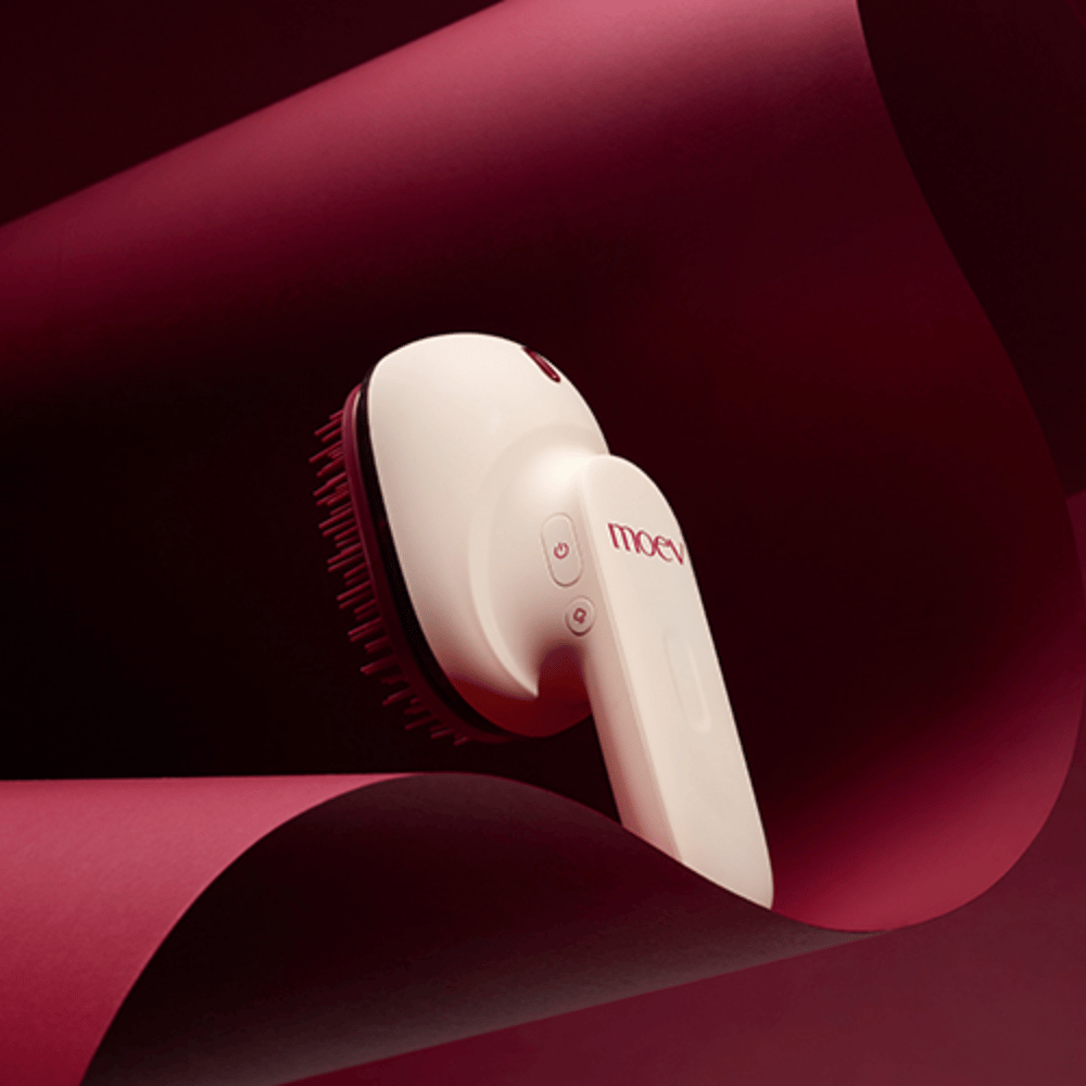 MOEV Hair Steamer Pro im eleganten Design vor rotem Hintergrund. Innovativer Haarpflegebürste, die Dampf und Wärme verwendet, um Glanz, Weichheit und gestärkte Haargesundheit zu verleihen.