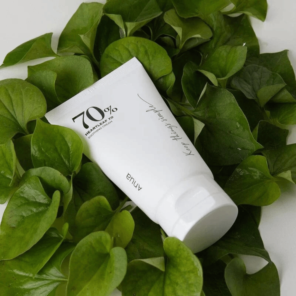 Eine Tube von Heartleaf 70% Soothing Cream ruht auf einem Bett aus grünen Blättern.