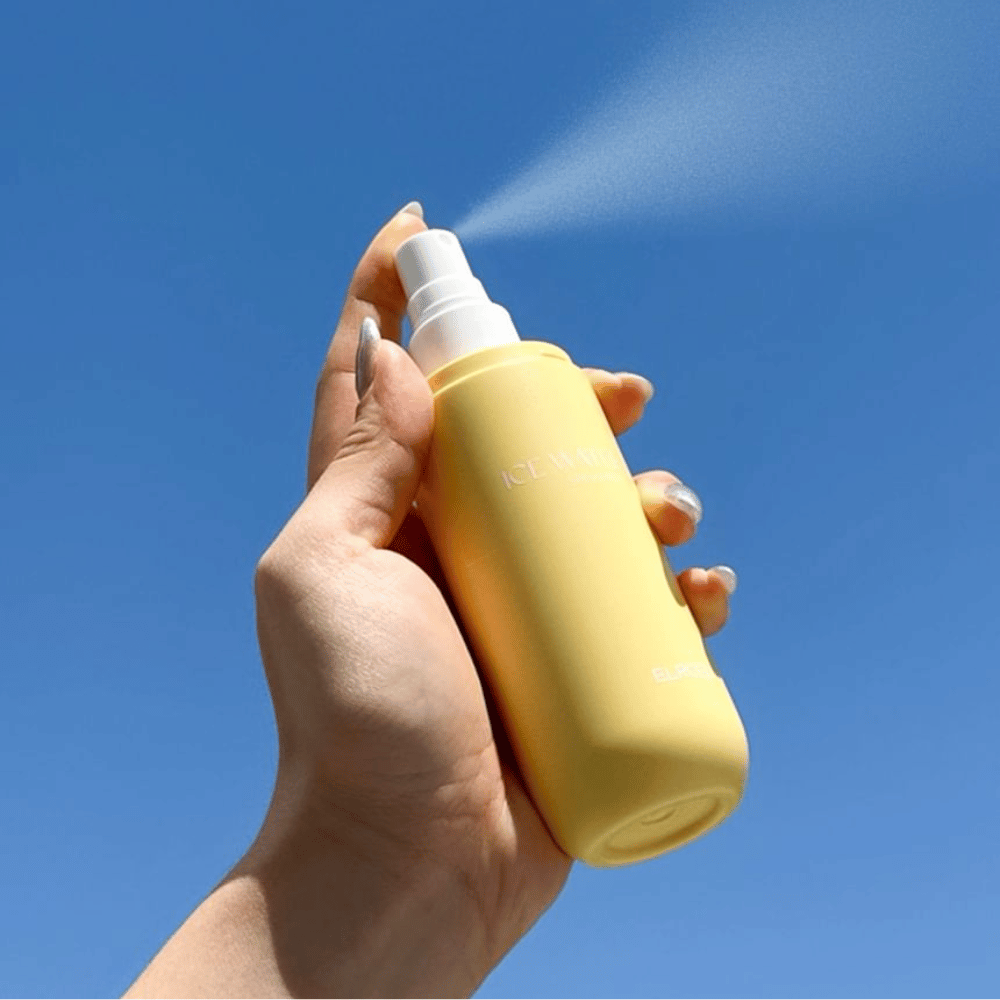 ELROEL Ice Water Sun Mist SPF 40 PA+++ Sonnenmist wird aus der Flasche vor blauem Himmel versprüht, leichter Sonnenschutz, der die Haut mit Feuchtigkeit versorgt und erfrischt