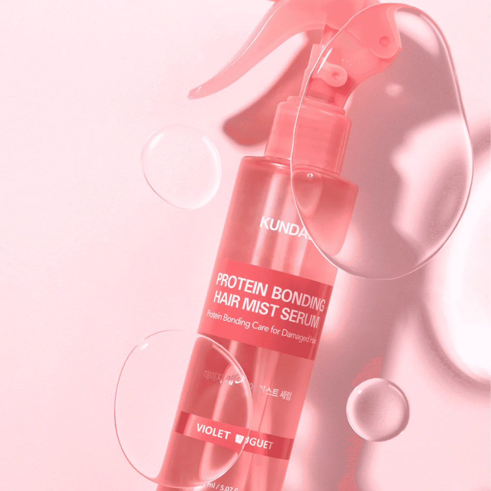 KUNDAL Protein Bonding Hair Mist Serum Violet Bouquet in rosa Sprühflasche, fotografiert vor rosa Hintergrund mit Wassertropfen.