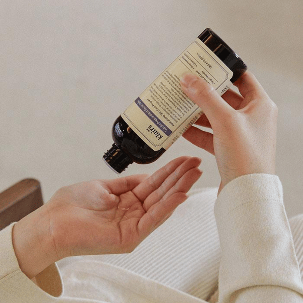 Eine Person hält eine Flasche von Klairs Supple Preparation Facial Toner kopfüber über ihrer Hand, bereit, das Produkt zu dosieren.