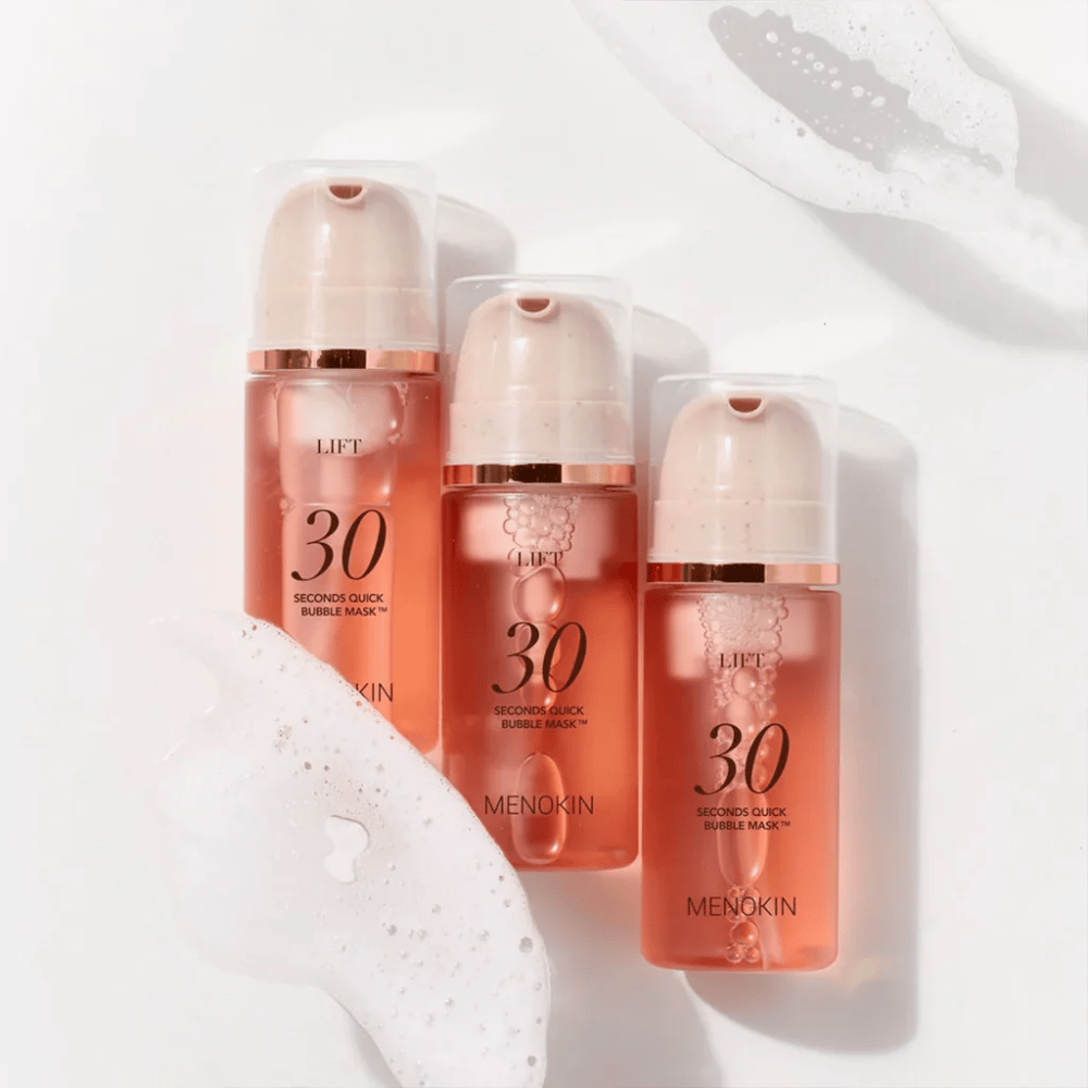 Ästhetisches Produktbild mit drei Flaschen von MENOKIN LIFT 30 Seconds Quick Bubble Mask, umgeben von weichem Schaum, der den sprudelnden und reinigenden Effekt hervorhebt.