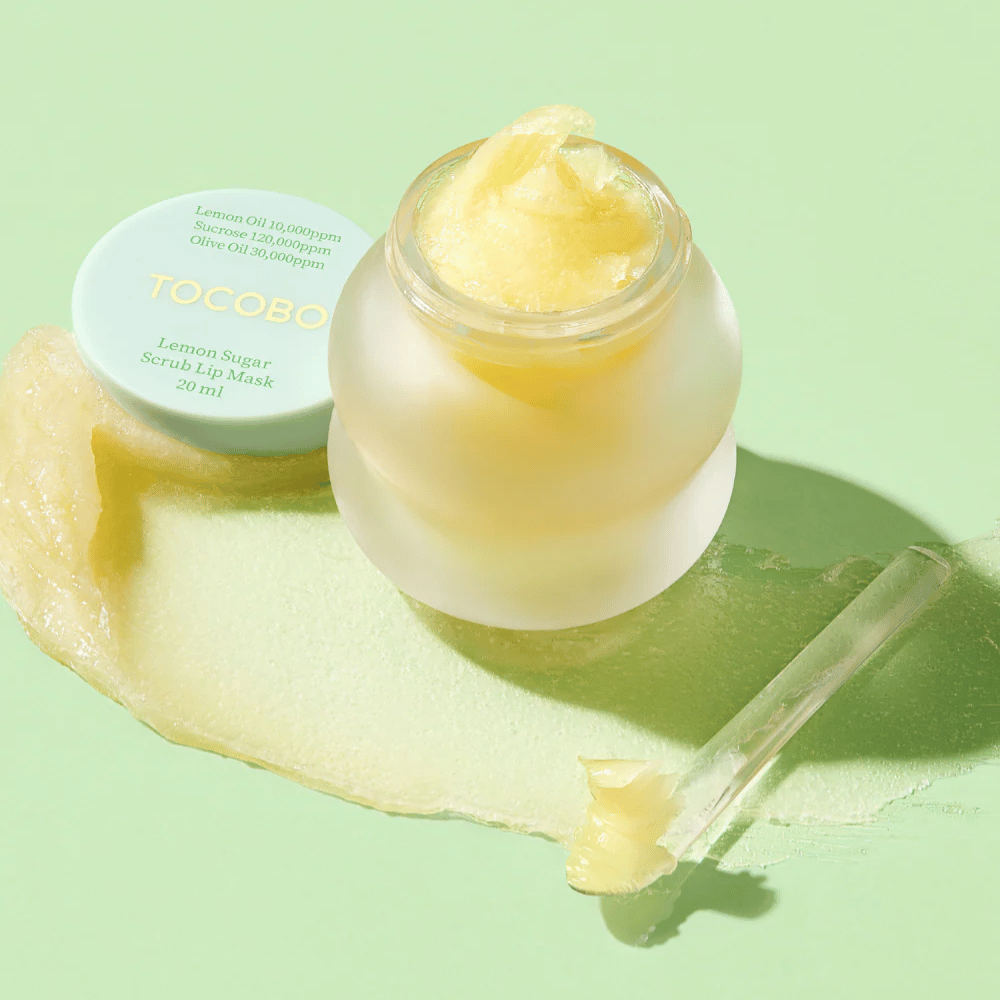 Offene Dose mit Tocobo Lemon Sugar Scrub Lip Mask auf einem grünen Hintergrund, mit deutlich sichtbarem Inhalt.