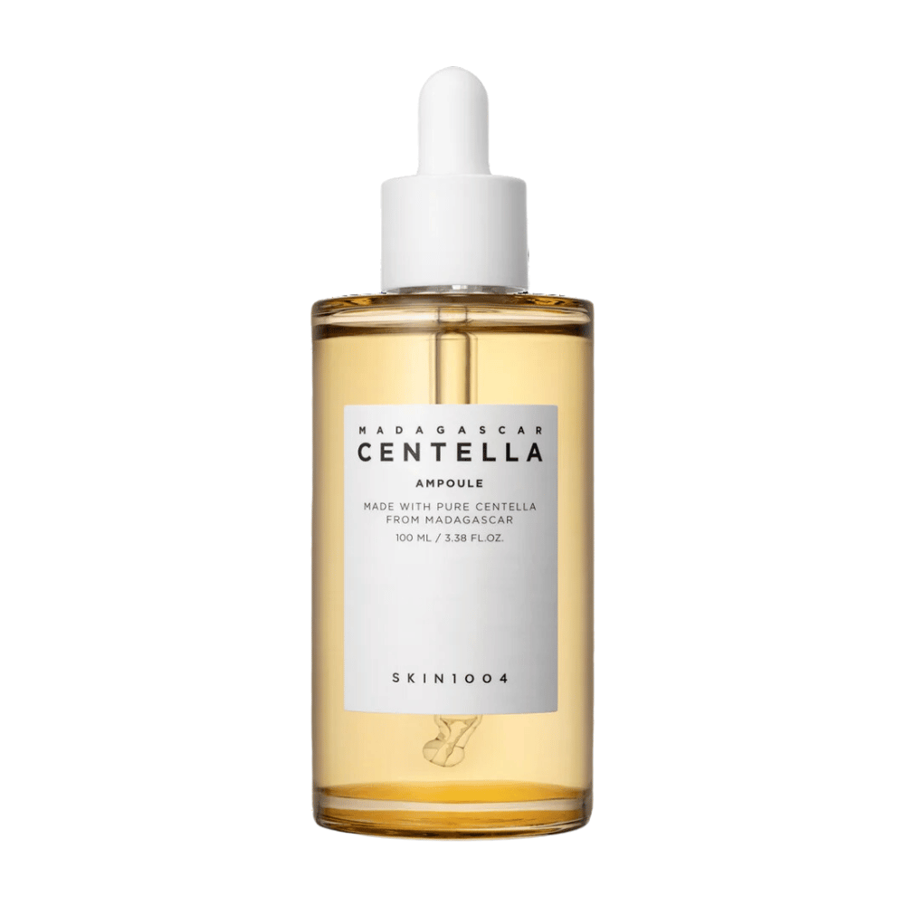 Das Bild zeigt eine Flasche mit "Madagascar Centella Asiatica 100 Ampoule" von SKIN1004. Die Flasche enthält 100 ml und behauptet, mit reinem Centella aus Madagaskar hergestellt zu sein. Das Produkt scheint ein Hautpflege-Serum zu sein, und das einfache Etikett vermittelt einen Eindruck von Reinheit und Natürlichkeit. Die Flasche mit Tropfverschluss deutet darauf hin, dass es sich um ein sorgfältig dosiertes Hautpflegeprodukt handelt.