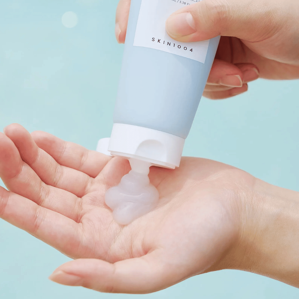 Das Bild zeigt jemanden, der eine klare, gelartige Substanz aus einer Tube drückt, die mit "SKIN1004 Madagascar Centella Hyalu-Cica Sleeping Pack" gekennzeichnet ist und 100 ml Produkt enthält.