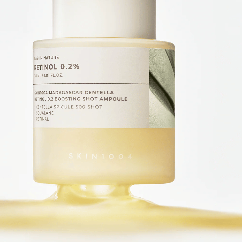 Nahaufnahme von SKIN1004 Madagascar Centella Retinol 0.2 Boosting Shot Ampoule, die die hellgelbe, seidig glatte Konsistenz des Retinol-Serums für nächtliche Hauterneuerung zeigt.