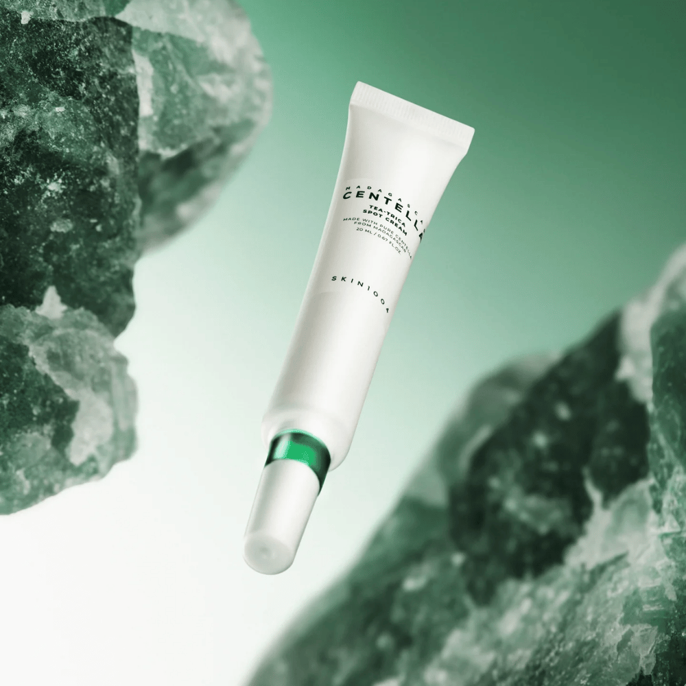 SKIN1004 Madagascar Centella Tea-Trica Spot Cream 20 ml gegen Akne und Pickel, Produktbild mit grünem Hintergrund und Kristallstruktur – beruhigende Punktbehandlung mit Centella Asiatica und tea tree.