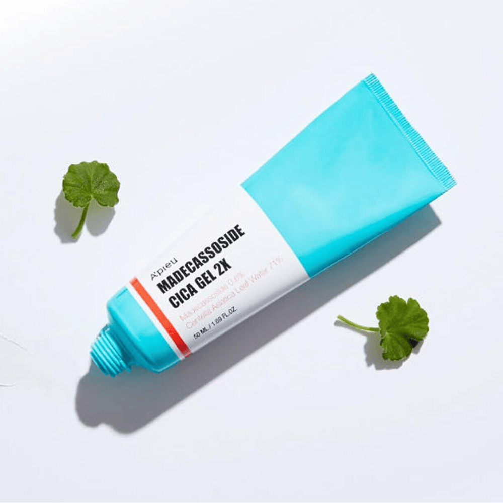 A’pieu Madecassoside Cica Gel 2X in blauer Tube mit weißem Etikett, umgeben von drei grünen Centella Asiatica-Blättern auf weißem Hintergrund.