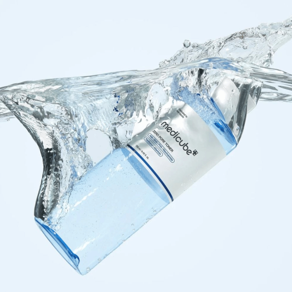 Medicube Zero Pore Toner 250 ml, exfolierendes gesichtswasser mit AHA, BHA und PHA. Transparente blaue Flasche, umgeben von einem großen Wasserspritzer.