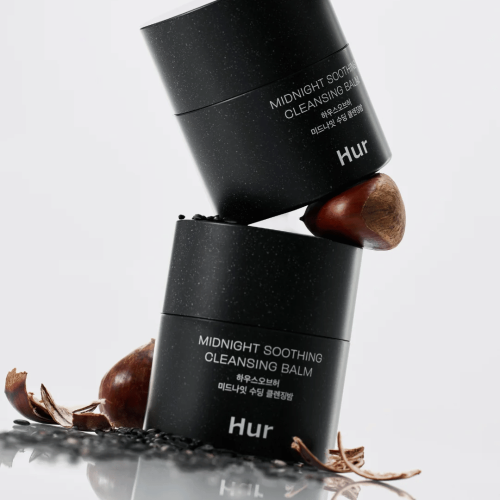 Zwei Dosen Wie Midnight Soothing Cleansing Balm gestapelt mit natürlichen Inhaltsstoffen. Nährender Reinigungsbalsam für die tägliche Reinigung empfindlicher Haut.