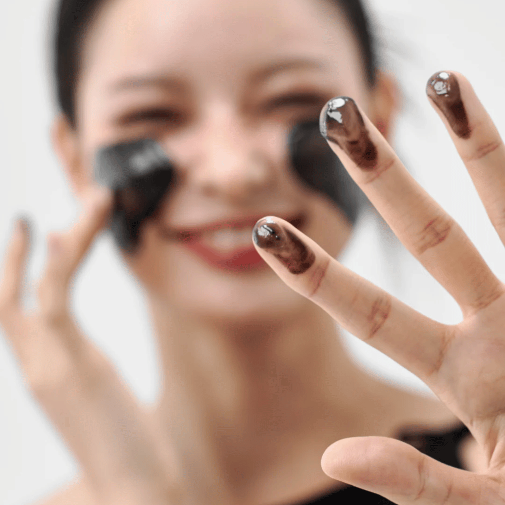 Modell trägt Wie Midnight Soothing Cleansing Balm auf der Haut auf. Cremiger Reinigungsbalsam, der tief reinigt und die Haut weich und ausgeglichen hinterlässt.