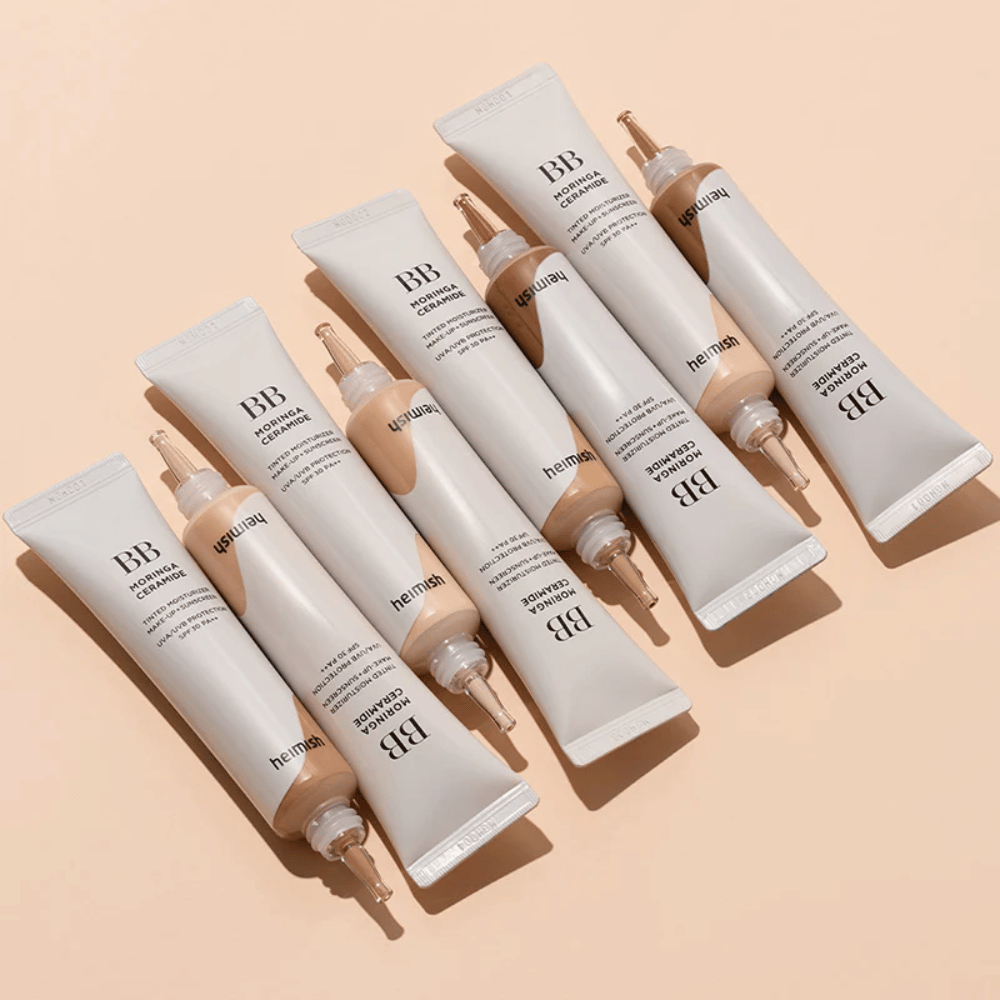 Mehrere Tuben von Heimish Moringa Ceramide BB Cream, angeordnet auf hellbeigem Hintergrund. Das Bild hebt die verschiedenen Farbtöne und das elegante, minimalistische Verpackungsdesign des Produkts hervor.