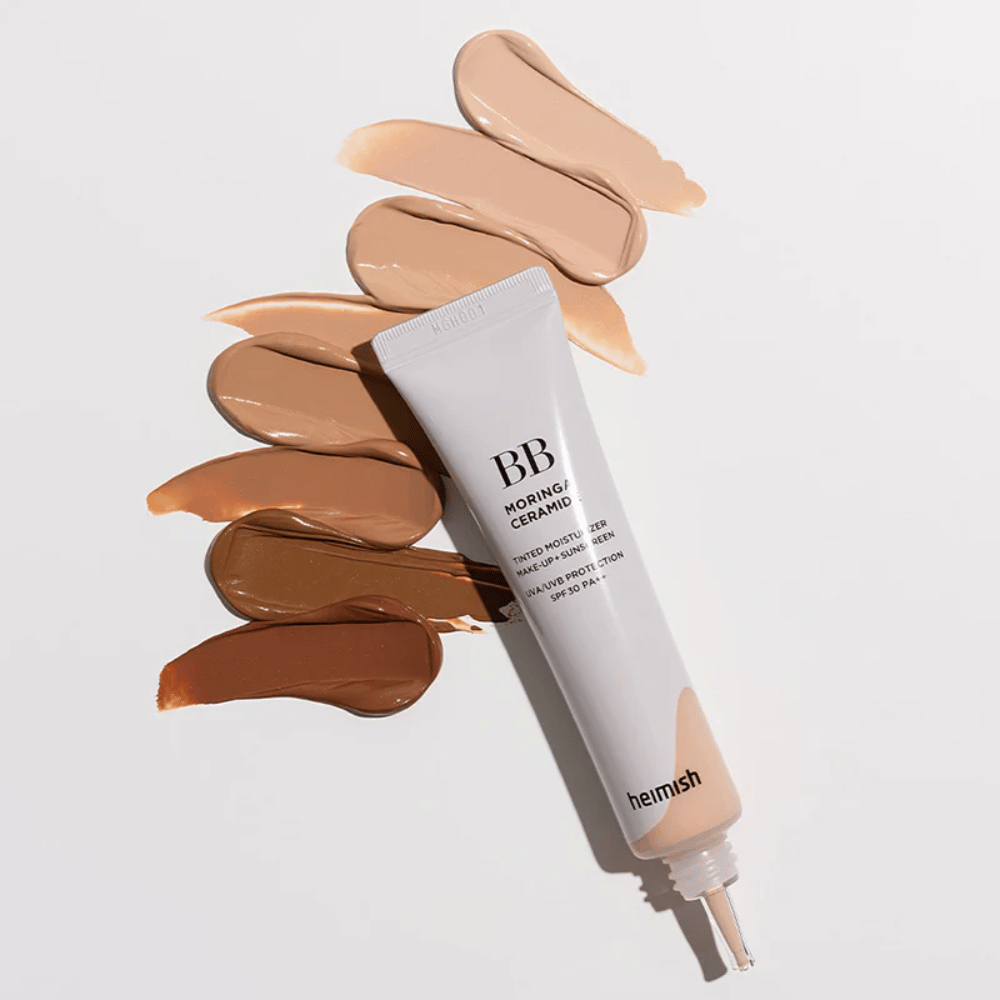 Heimish Moringa Ceramide BB Cream, umgeben von mehreren Farbmuster in verschiedenen Hauttönen. Das Bild zeigt die breite Farbpalette des Produkts und die cremige Konsistenz, die eine natürliche Deckkraft und einen ebenmäßigen Hautton verleiht.