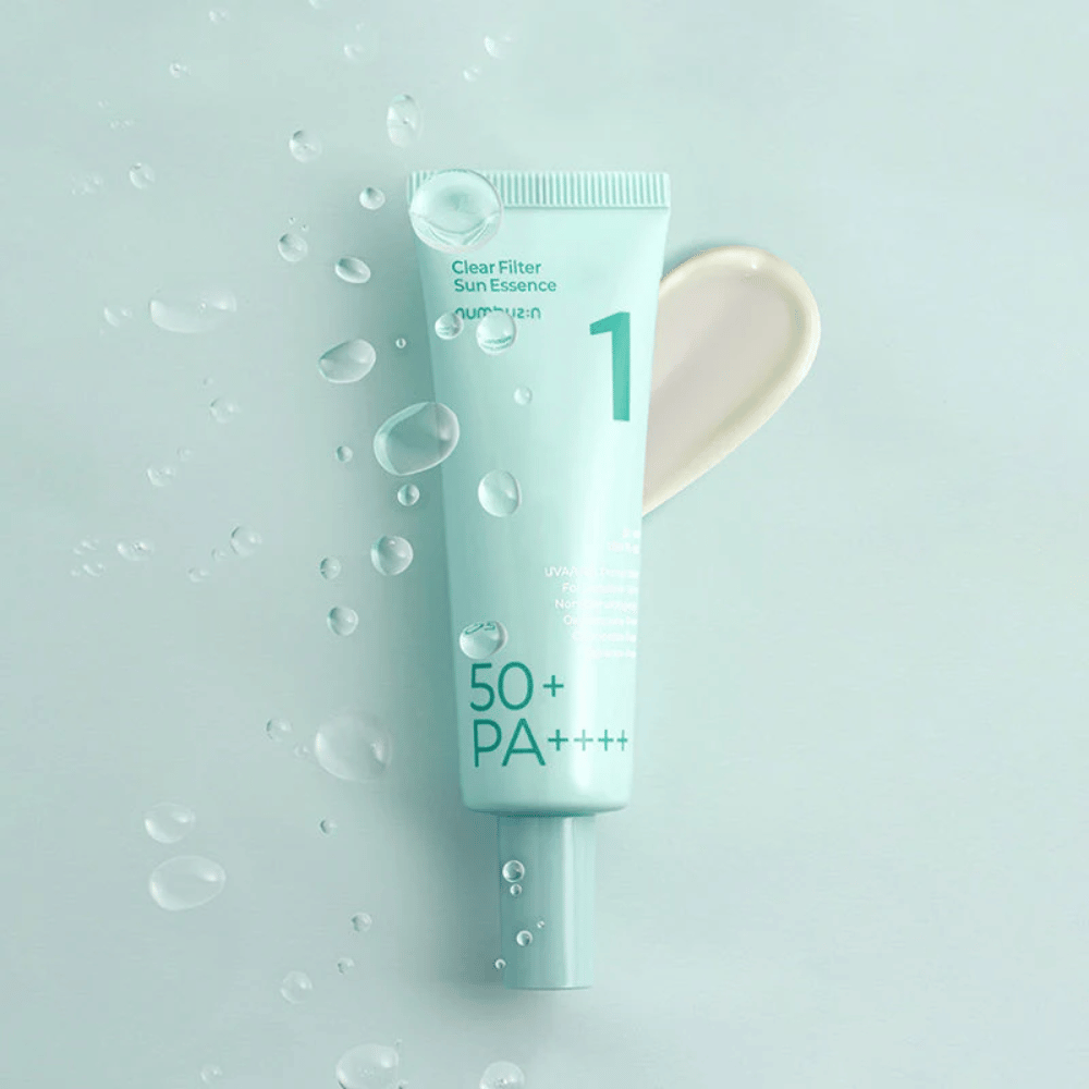 Eine hellblaue Tube mit No.1 Clear Filter Sun Essence SPF 50+ PA++++. Die Tube ist mit Wassertropfen verziert und ein Klecks des Produkts wird daneben gezeigt. Das Produkt ist so konzipiert, dass es einen hohen Sonnenschutzfaktor und Schutz vor UVA/UVB-Strahlen bietet.