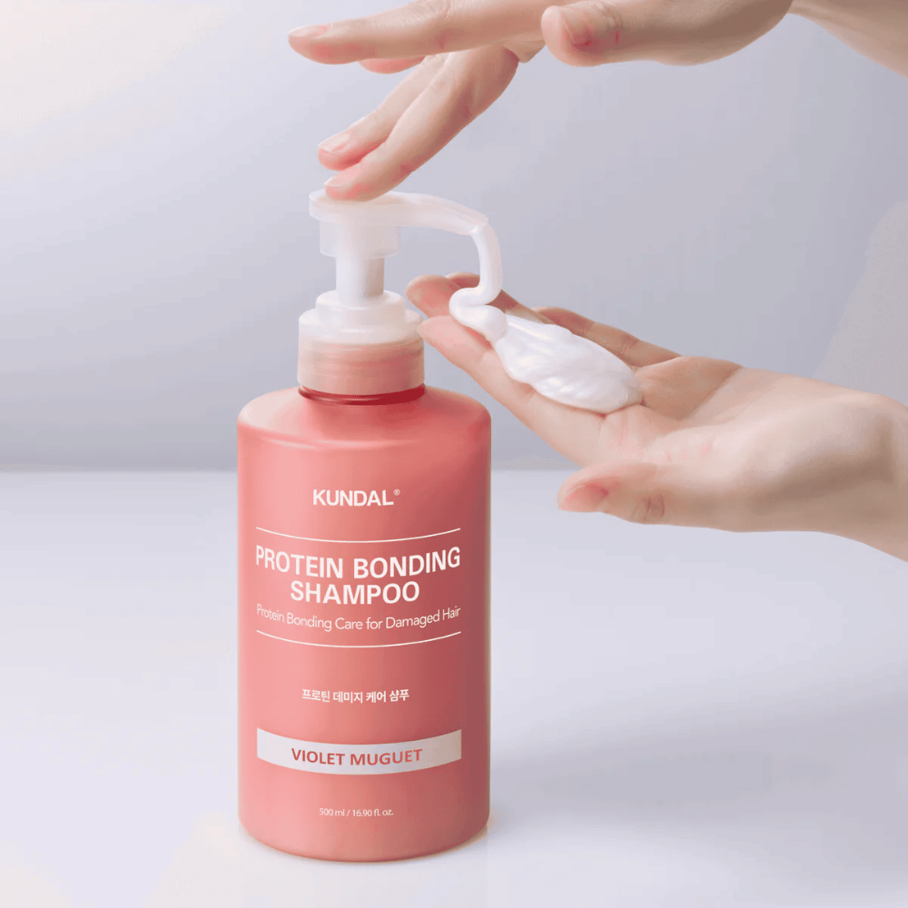 Hand pumpt KUNDAL Protein Bonding Shampoo Violet Muguet in cremiger Konsistenz, reparierendes Shampoo für geschädigtes Haar.