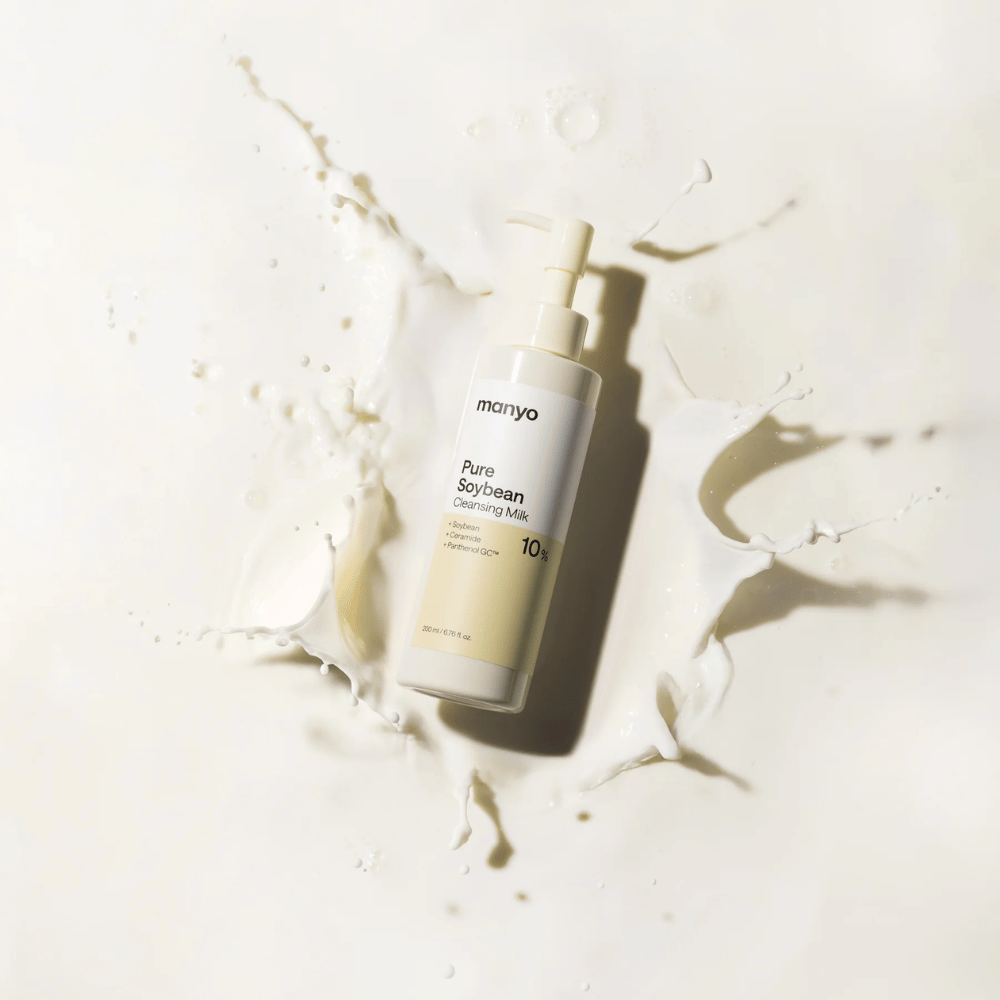 1. Ma:nyo Pure Soybean Cleansing Milk – milde Reinigungsmilch mit Soja in Pumpflasche, umgeben von Milchspritzern vor hellem Hintergrund